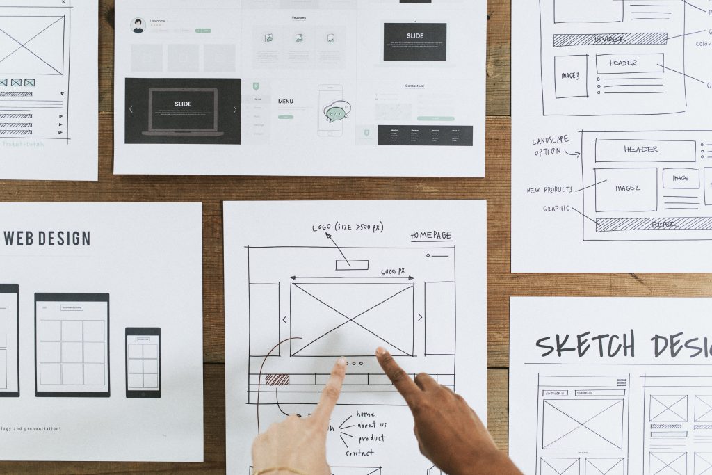 Hands reviewing a website design plan on paper