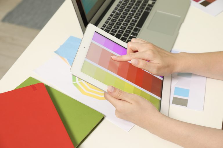 Website designer choosing colours from a palette beside a tablet