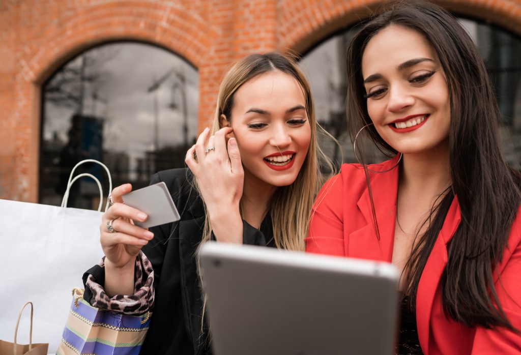 Two friends shopping online together with a digital tablet