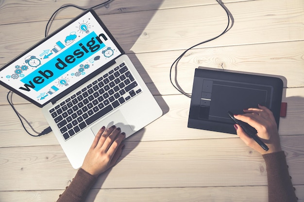 Designer sketching a website layout beside a laptop