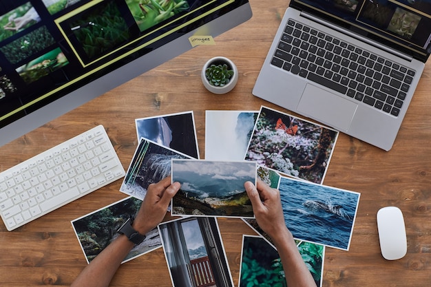 Hands sorting printed photographs on a wooden desk