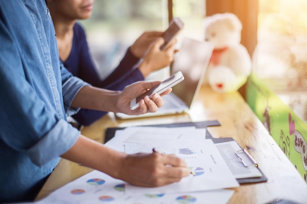 Colleagues reviewing charts and phones on an office desk