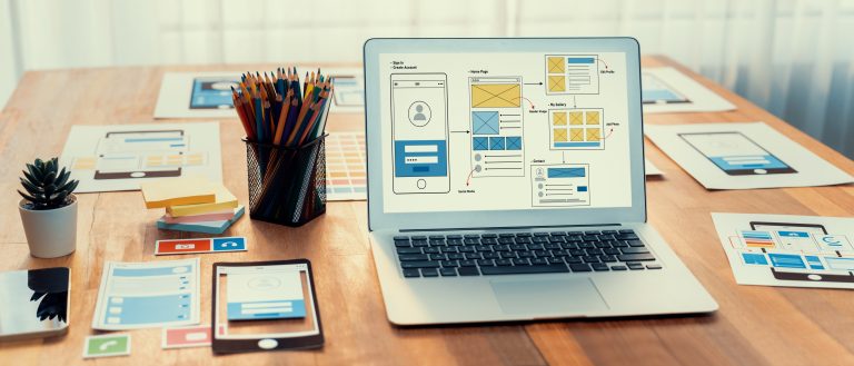 Website redesign wireframes on a laptop and desk