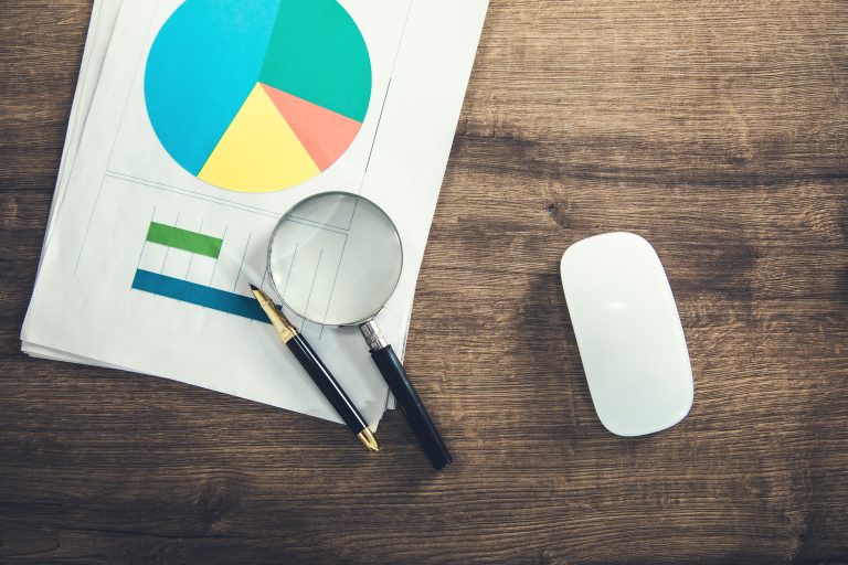 Magnifying glass and pen on business graphs