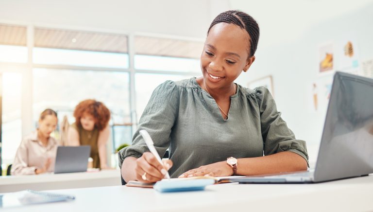 Business owner writing marketing ideas in a notebook
