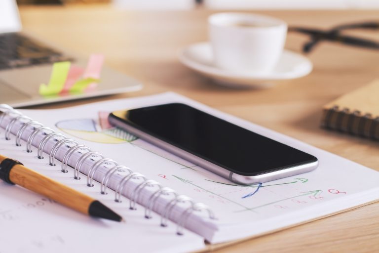 Phone and notepad used for planning social media activity