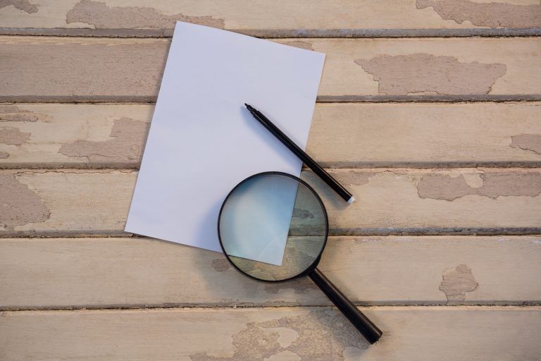 Magnifying glass and pencil on paper representing careful review