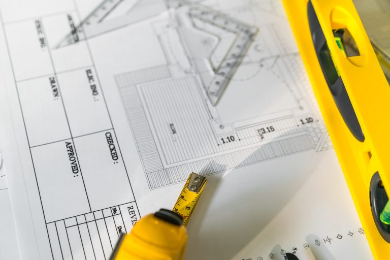 Construction plans with helmet and drawing tools