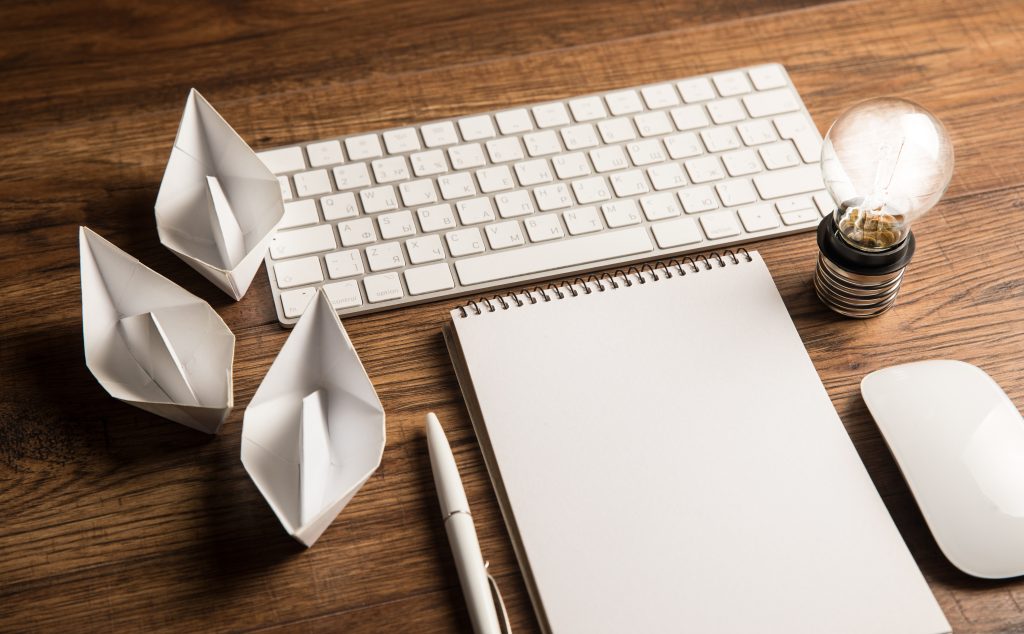 Notebook, paper ideas and a light bulb on a desk