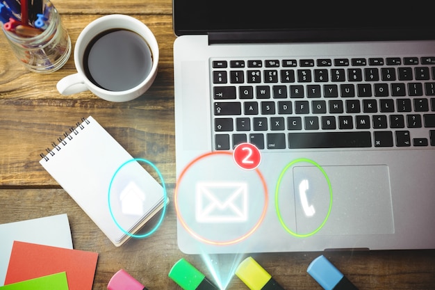 Laptop and desk showing email and phone contact icons
